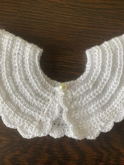 Another view of the classic white crochet collar, perfect for adding a sophisticated touch to a dark top or dress.