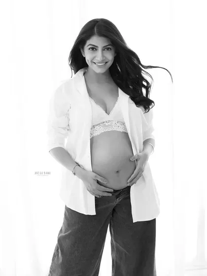 A modern and confident solo portrait. The contrast in this black and white image highlights the open shirt and baby bump, creating a chic and stylish look.