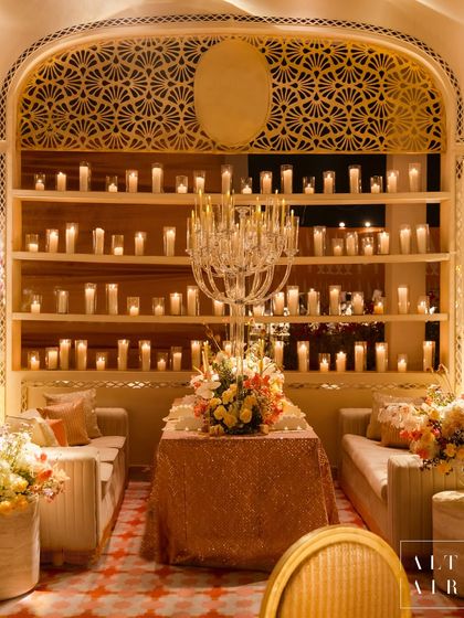 A cozy seating arrangement at the 'Sitara Mahal' dinner, with a crystal candelabra and a backdrop of countless candles. The design focused on creating a royal ambiance with ivory hues and intricate mirror work.