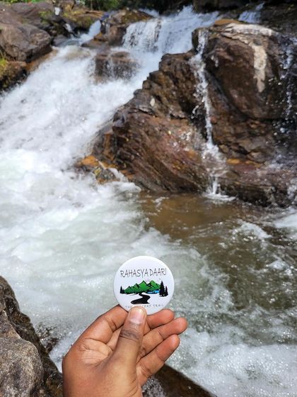 The Rahasya Daari badge in front of a small, powerful cascade.