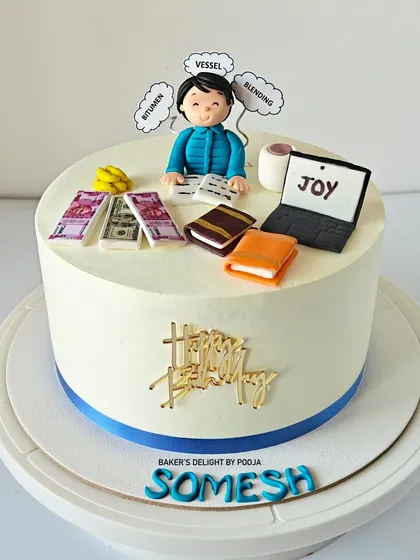 The full view of the personalized cake for Somesh, which includes toppers representing his work, money, books, and a laptop showing "Joy."