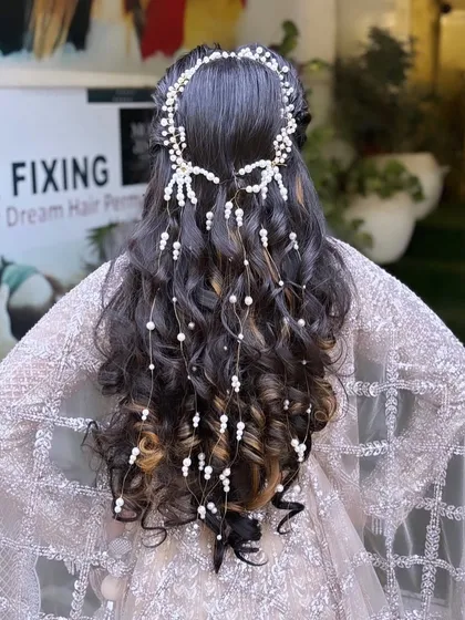 A bridal hairstyle is a work of art. This intricate hairdo features beautiful curls woven with delicate pearl accessories, creating a look that is both romantic and incredibly detailed from every angle.