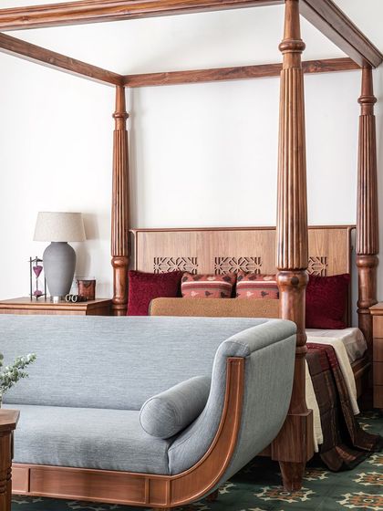 The master bedroom is a perfect harmony of patterns, colors, and textures. A fresh patterned green flooring sets the mood, beautifully complementing the rich teak furniture, including a colossal four-poster bed designed to match the client's grand personality.