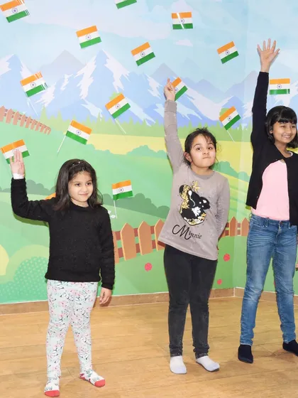 Three girls wave small Indian flags during a group activity for Independence Day.