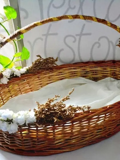 This is an example of a custom-decorated hamper basket, perfect for weddings or special events. The sturdy oval cane basket is adorned with flowers and lined with fabric, ready for gifting.