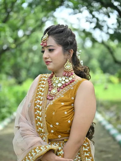 A close-up of the mustard yellow lehenga, focusing on the intricate blouse embroidery and the beautiful pink and gold jewellery.