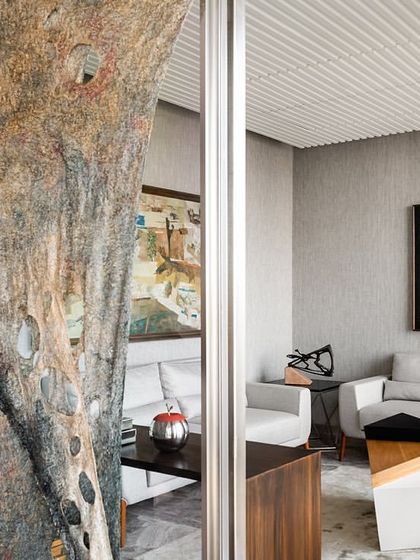 The top floor of the Stainless Steel Office, reserved for directors, has a distinct design aesthetic. This lounge area features a unique textured wall hanging and a striking grey marble floor, setting it apart from the general office spaces below.