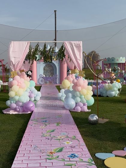 A beautiful outdoor party entrance with a custom printed walkway and pastel balloon arrangements, setting a whimsical tone for the event.