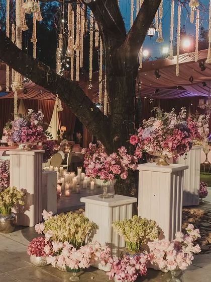 We use natural elements as part of the decor. Here, a large tree becomes a centerpiece, adorned with hanging floral strings and surrounded by lush arrangements.