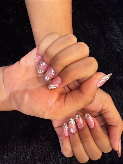 A soft and delicate floral design. This set features a shimmering pink base with hand-painted white flowers and subtle silver glitter stripes.