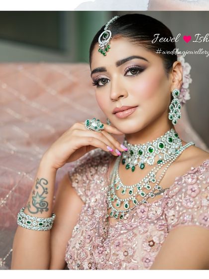 A close-up of this breathtaking bridal look. The emerald and diamond set includes a choker, a layered necklace, statement earrings, and a maang tikka, all designed to create a look of pure opulence.