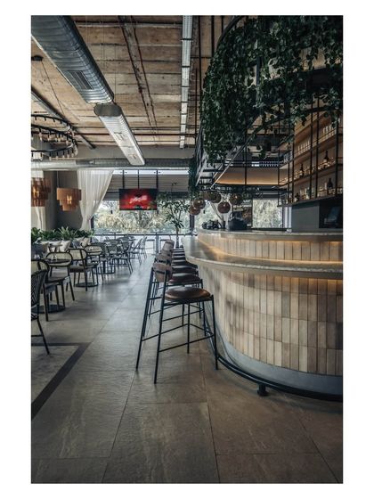 The long, curved bar is an understated focal point, clad in muted subway tiles and softly lit from below. As evening approaches, it becomes a glowing centerpiece that draws people together.