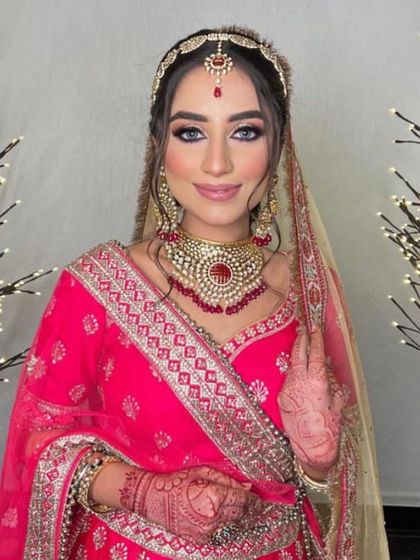 A beautiful smile from our happy client. Her blue eyes pop against the pink tones of her makeup and outfit. Book your slot with us as soon as possible.