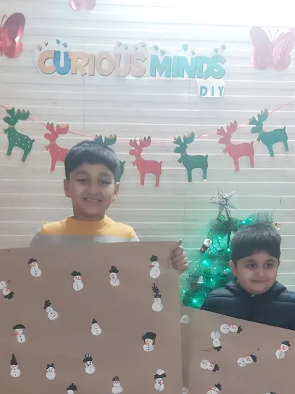 Two boys happily display the festive wrapping paper they made. Our workshops are a great way for friends and siblings to collaborate and share in the holiday excitement.