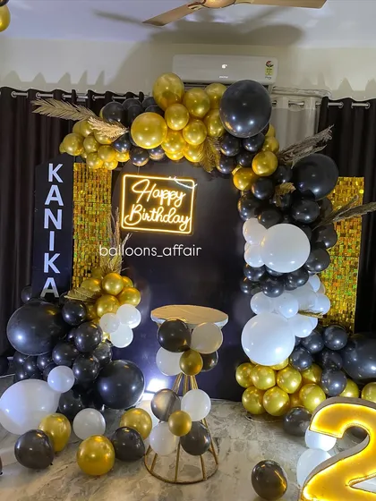 A full view of the stylish 28th birthday setup, showing the balloon arch and cake table.