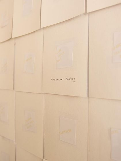 A close-up of the "Directory of the Outsiders" installation, where stories are subtly printed on paper. The work invites quiet contemplation on themes of exclusion and memory.