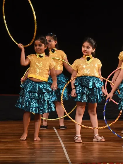A group of young girls in sparkling costumes prepares for their hoop dance performance. We incorporate creative props to make routines visually interesting and fun for the performers.