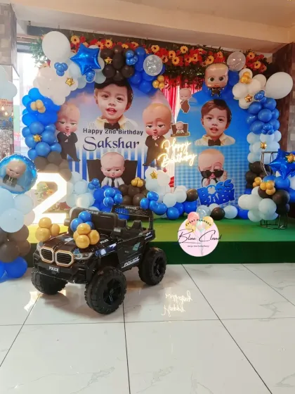 A Boss Baby themed second birthday with a custom photo backdrop, balloon arch, and a toy police jeep.