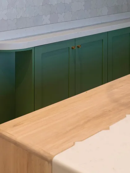 The corner of this kitchen shows how we blend materials. The wooden island top meets the clean white countertop, while the green cabinets and patterned backsplash create a cohesive and personal feel.