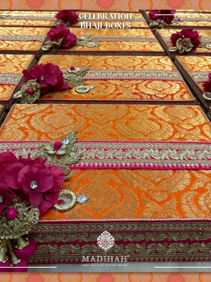 A display of the Celebration Bhaji Boxes, ready for a large event. The rich orange fabric and floral details create a stunning visual impact.