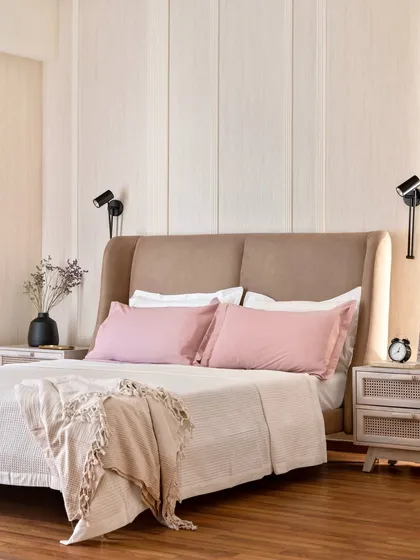 I designed this bedroom to be a true personal sanctuary. The combination of a soft upholstered headboard, warm wooden flooring, and delicate pink bedding creates a tranquil atmosphere. The fluted wall paneling adds texture and a touch of modern elegance, making it a perfect space to unwind.
