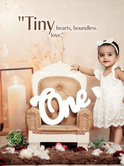 A lovely first birthday portrait in our studio. The setup with soft lighting, candles, and flowers creates a warm and celebratory atmosphere.