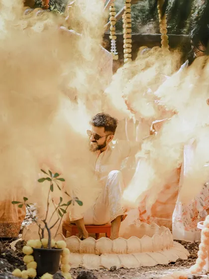 An atmospheric shot of the groom amidst a cloud of yellow smoke during his Haldi ceremony, creating a dramatic and memorable image.