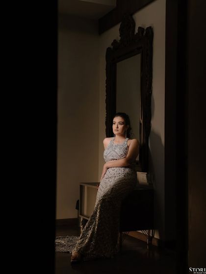 A quiet, elegant portrait of the bride, Sumanya, seated in a dimly lit room before her engagement.
