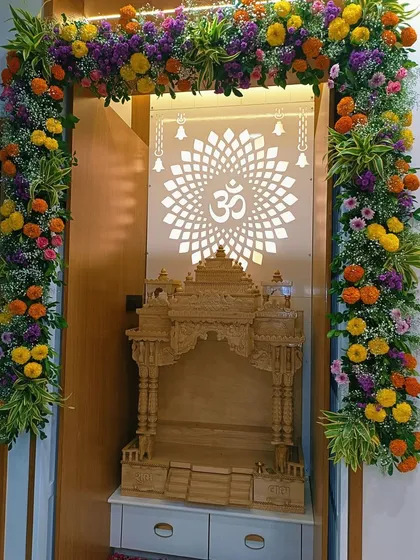We decorated this beautiful home mandir with a full floral arch made of bright marigolds, purple statice, and baby's breath. The design complements the intricate wooden temple and the backlit 'Om' panel, creating a truly divine prayer space.