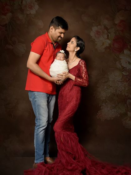 A fine art family portrait with a newborn against a painted canvas backdrop. The mother's elegant lace gown and the rich colors create a classic, painterly feel for this special first portrait.