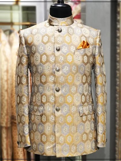 A Jodhpuri jacket in a gold and silver brocade with a hexagonal pattern. This is a rich and festive piece, perfect for a wedding celebration.