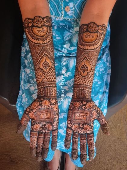 A full view of a bridal mehendi design where the palms feature the names "Trupti" and "Girish" and the word "Vivah". The arms are decorated with floral patterns and traditional symbols.