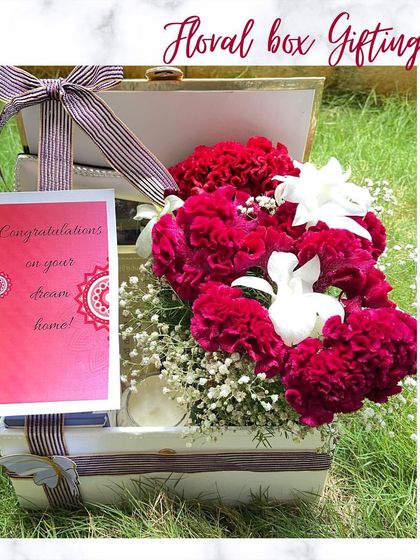 A floral box is another beautiful option for a housewarming gift. This white trunk box opens up to reveal a stunning arrangement of red carnations and a congratulatory note.
