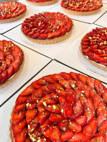 A bulk order of our delightful strawberry tarts, each one a perfect spiral of fresh berries and pistachios.