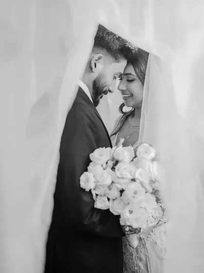 An intimate black and white portrait of the couple under the bride's veil. This classic shot is all about romance and connection, creating a timeless memory.