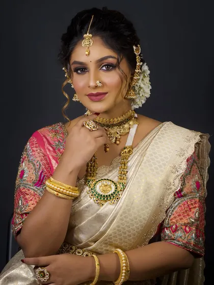 A portrait of a South Indian bride. The makeup is designed to complement the rich silk saree and the heavy gold temple jewellery.