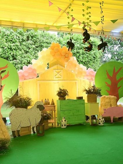 The main backdrop for the Boho animal party was a charming barnyard scene, with cutouts of a horse, sheep, and pig, set against a soft yellow barn facade.