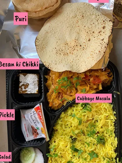 A detailed look inside one of my exhibition meal plates, featuring lemon rice, cabbage masala, a sweet besan ki chikki, salad, pickle, and a puri.