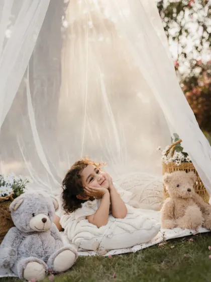A little girl strikes a dreamy pose in her outdoor teepee, surrounded by her furry friends. A perfect portrait for a kids' photography portfolio.