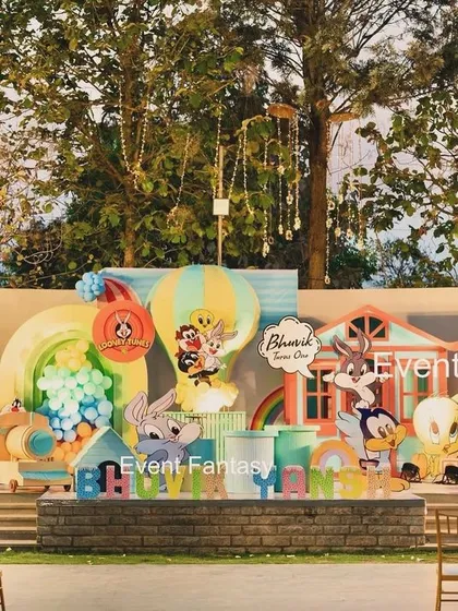 That's all, folks! A grand Looney Tunes first birthday celebration for Bhuvik. This expansive outdoor stage brings the classic cartoon to life with large cutouts of Bugs Bunny, Sylvester, Daffy Duck, and the whole gang, complete with colorful balloon art and themed houses.