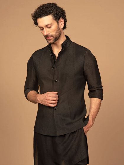 A sleek and modern all-black kurta pajama set. The jacket features unique seam detailing, giving a contemporary edge to a classic silhouette. This is for the man who appreciates minimalist design.