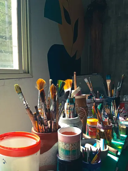 Sunlight streaming into the studio, illuminating pots filled with brushes of all shapes and sizes. This is the heart of our workspace.