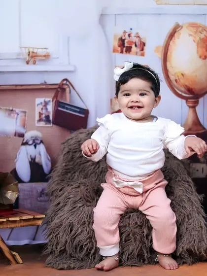 A happy, expressive baby girl enjoying her vintage traveler-themed photoshoot.