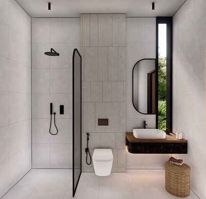 A bathroom design for our Vagator Villas project, featuring clean lines and a minimal material palette. A simple glass partition separates the shower, while a floating vanity and a narrow vertical window maintain a sense of openness and light.