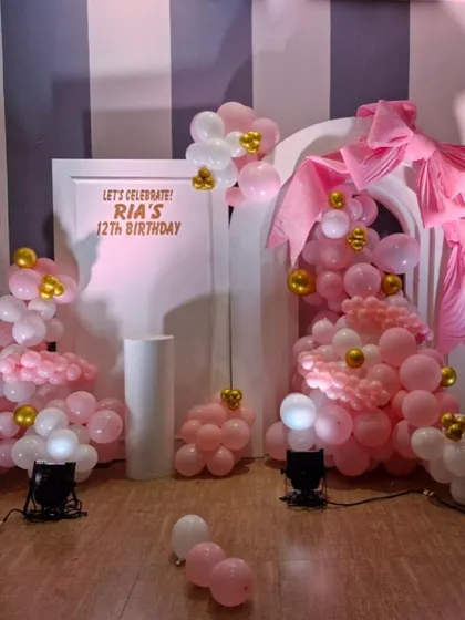 This setup for Ria's 12th birthday combines the bow trend with a pink and gold balloon arrangement and a custom-lit backdrop for a fun and girly celebration.