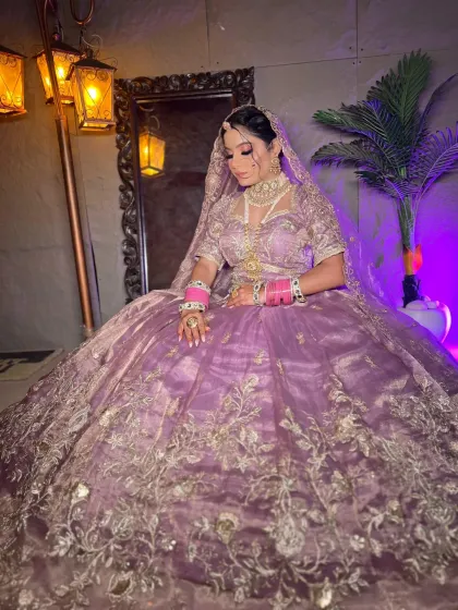 A seated pose of a bride in the lilac organza lehenga, showing the volume of the skirt and the intricate jewelry.