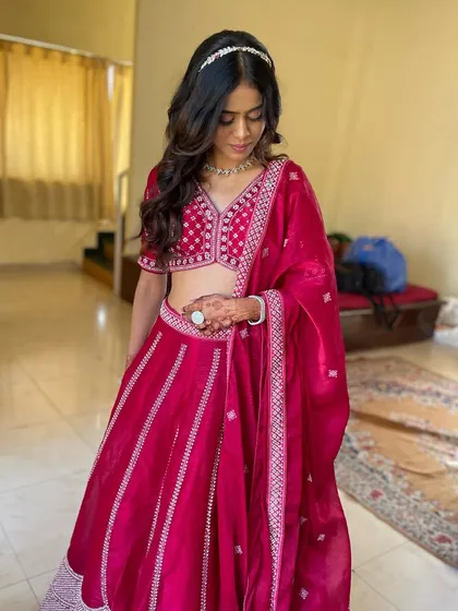 A full view of this lovely look. The soft waves and simple hair accessory are the perfect complement to her vibrant pink lehenga.