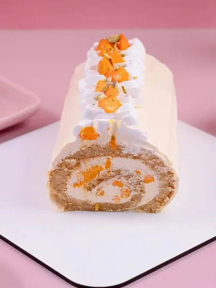 A mango swiss roll cake, sliced to show the swirl inside. This shot is all about showing the beautiful cross-section and texture of the dessert.