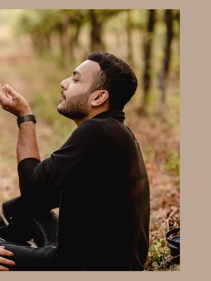A poetic, solo portrait of the groom-to-be, seemingly catching raindrops in a forest setting. It's a moody and artistic shot.