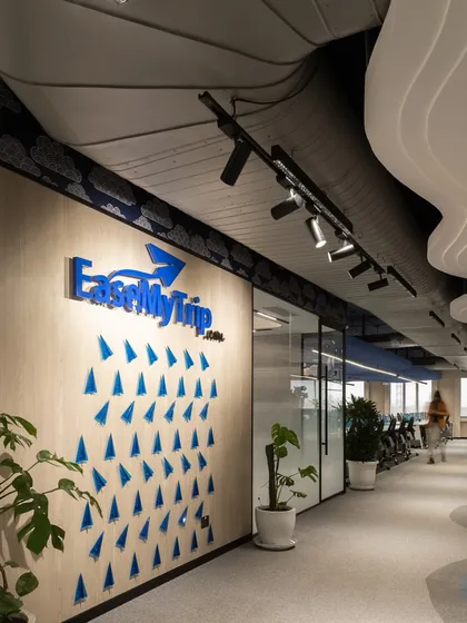 The entrance corridor immediately introduces the brand identity with a three dimensional logo and graphic wall art. Potted plants and curved ceiling details create a welcoming and dynamic first impression for visitors and employees.